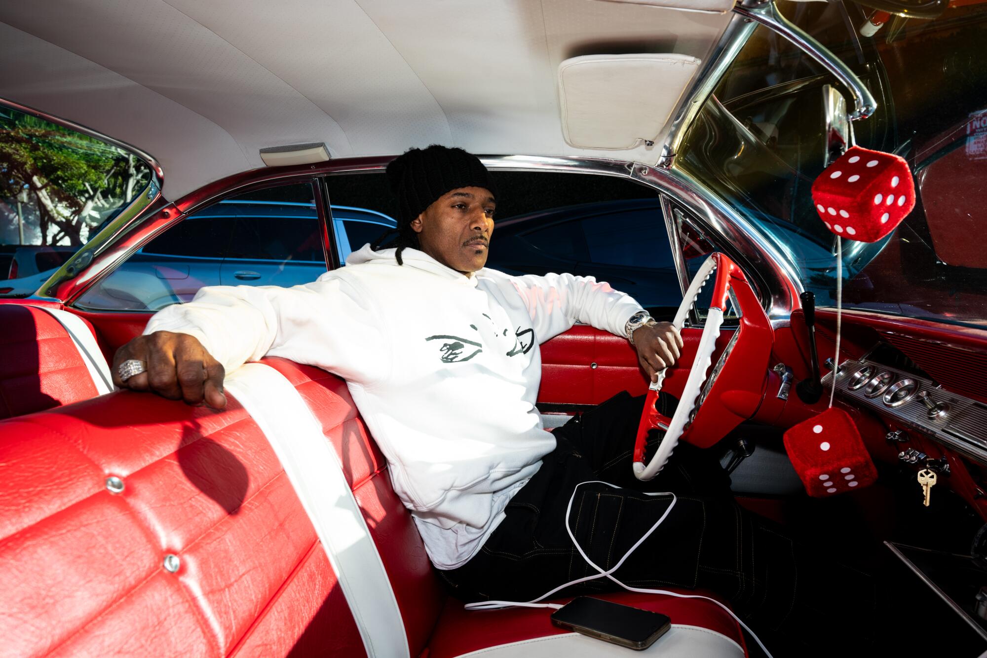 A rapper sits in the front seat of a car