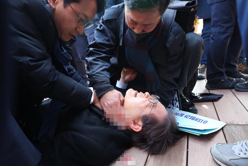 Lee Jae-myung, leader of the main opposition Democratic Party, lies down after he was stabbed by an assailant on the left side of his neck during a visit to the construction site of an airport on Gadeok Island off the southeastern port city of Busan on Tuesday/ Photo by Yonhap