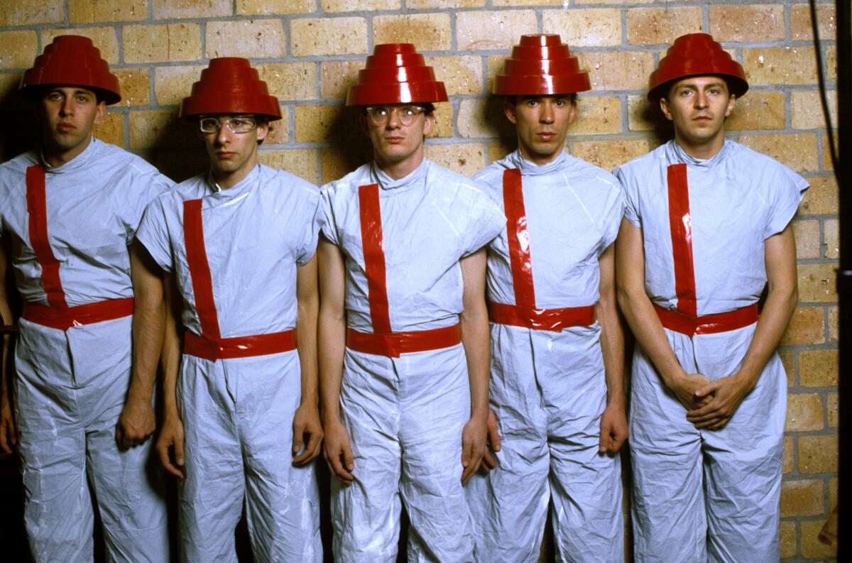 A band in red plastic hats waits to be deployed.