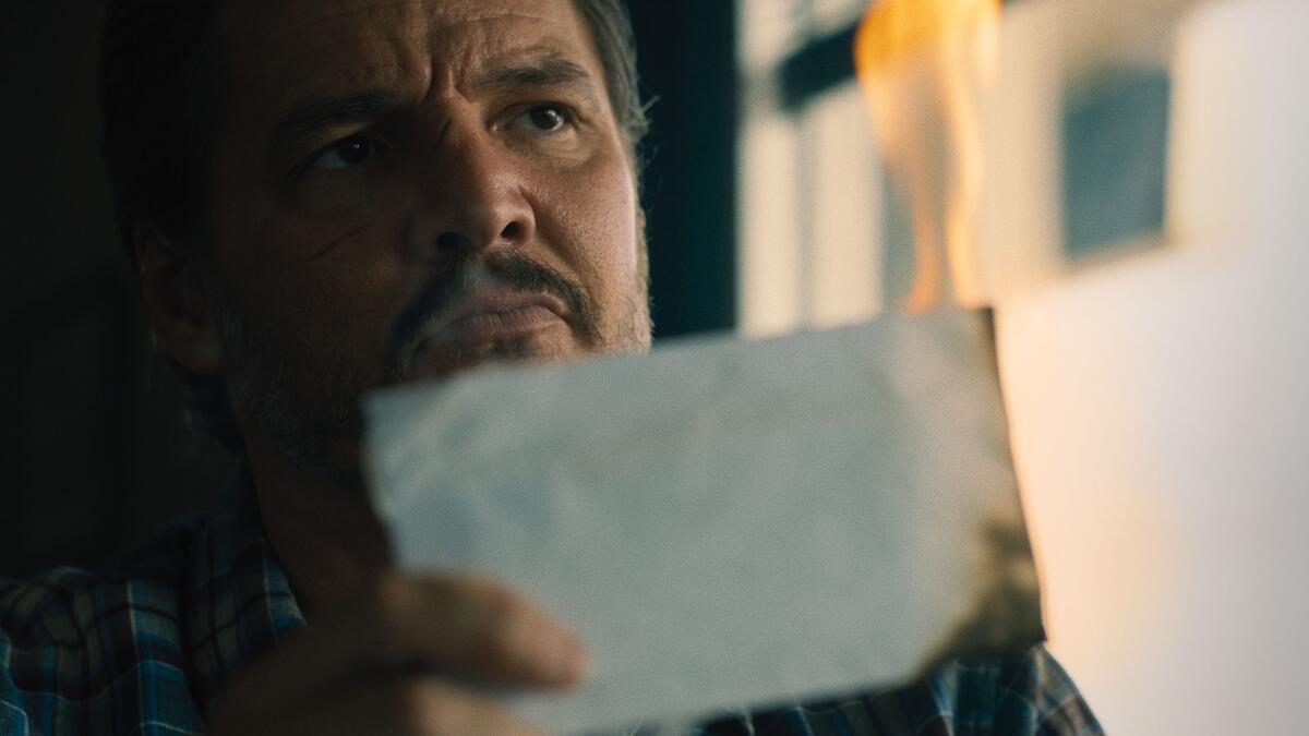 A man looks at a burned piece of paper.