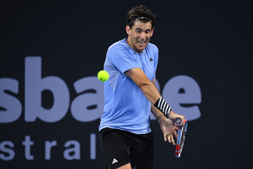 Dominic Thiem looks at a tennis ball and holds back his racquet to hit it.