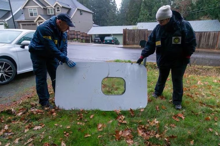 Men look at a plane door on a lawn.