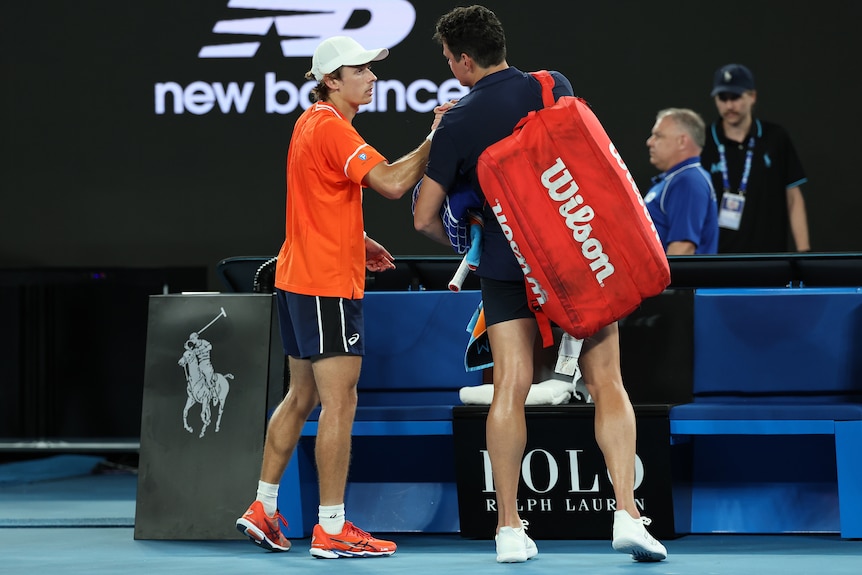 Alex de Minaur oats Milos Raonic on the shoulder.