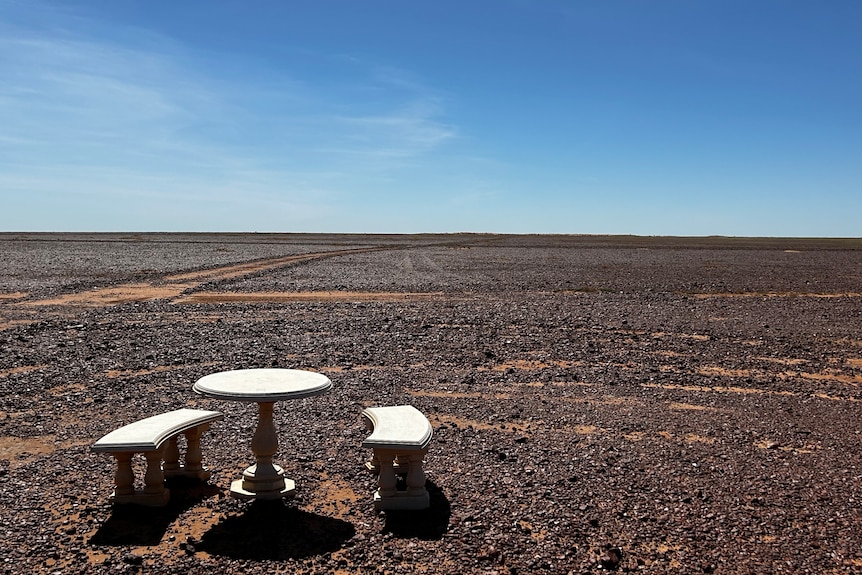 A table and some chairs in the desert.