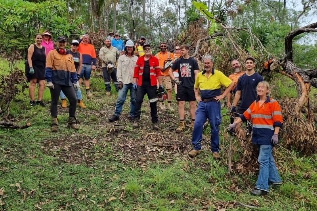 A group of people with chainsaws posing in front of fallen trees