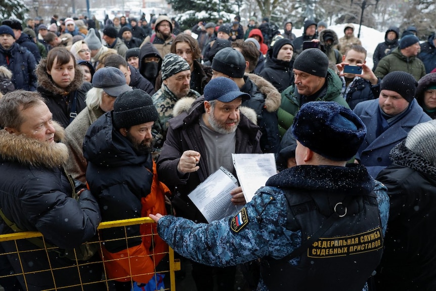 A large crowd of people talking to police