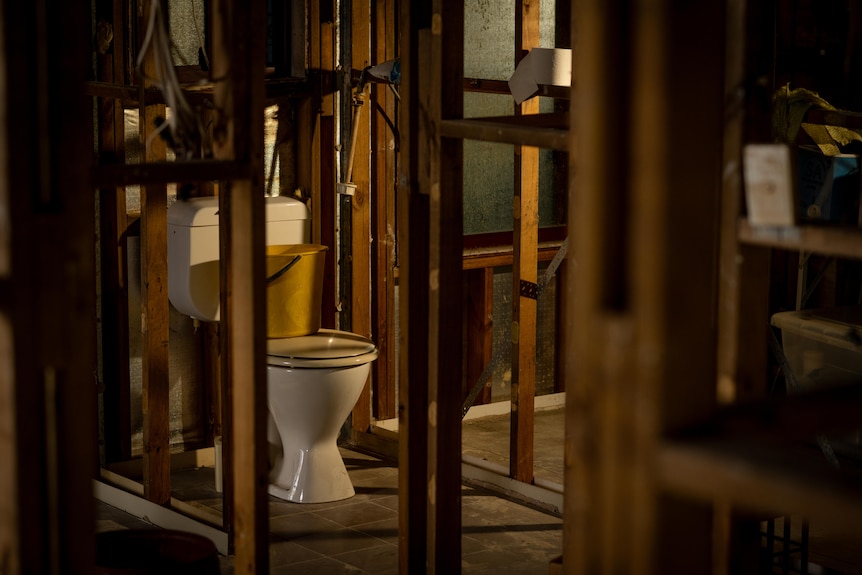 A toilet in a bathroom without any walls.