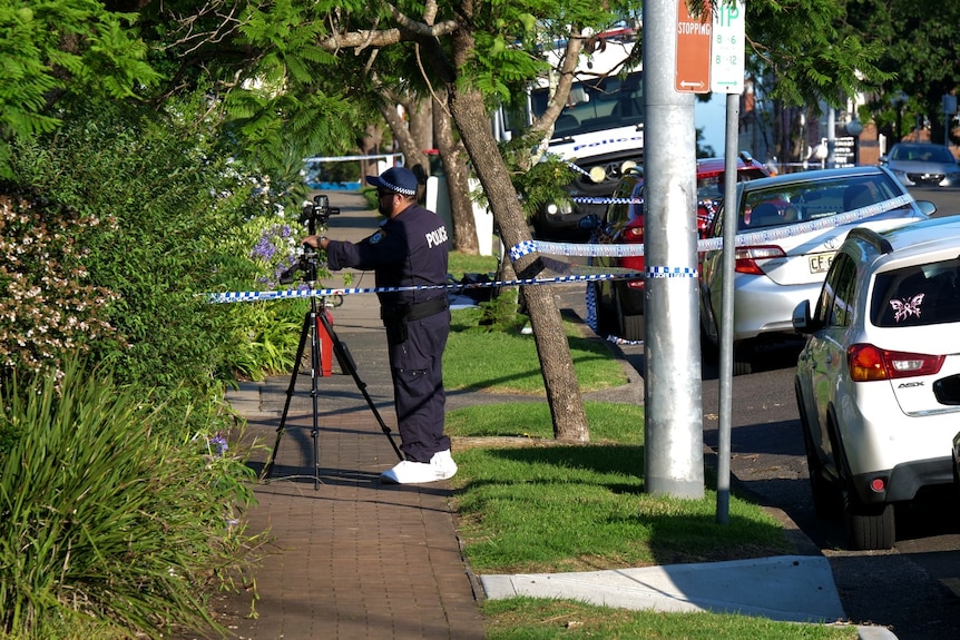 Police officer with camera standing on brick footpath