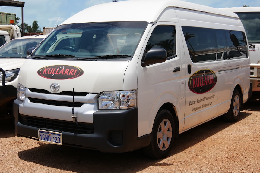 A white mini-van with a logo on the bonnet