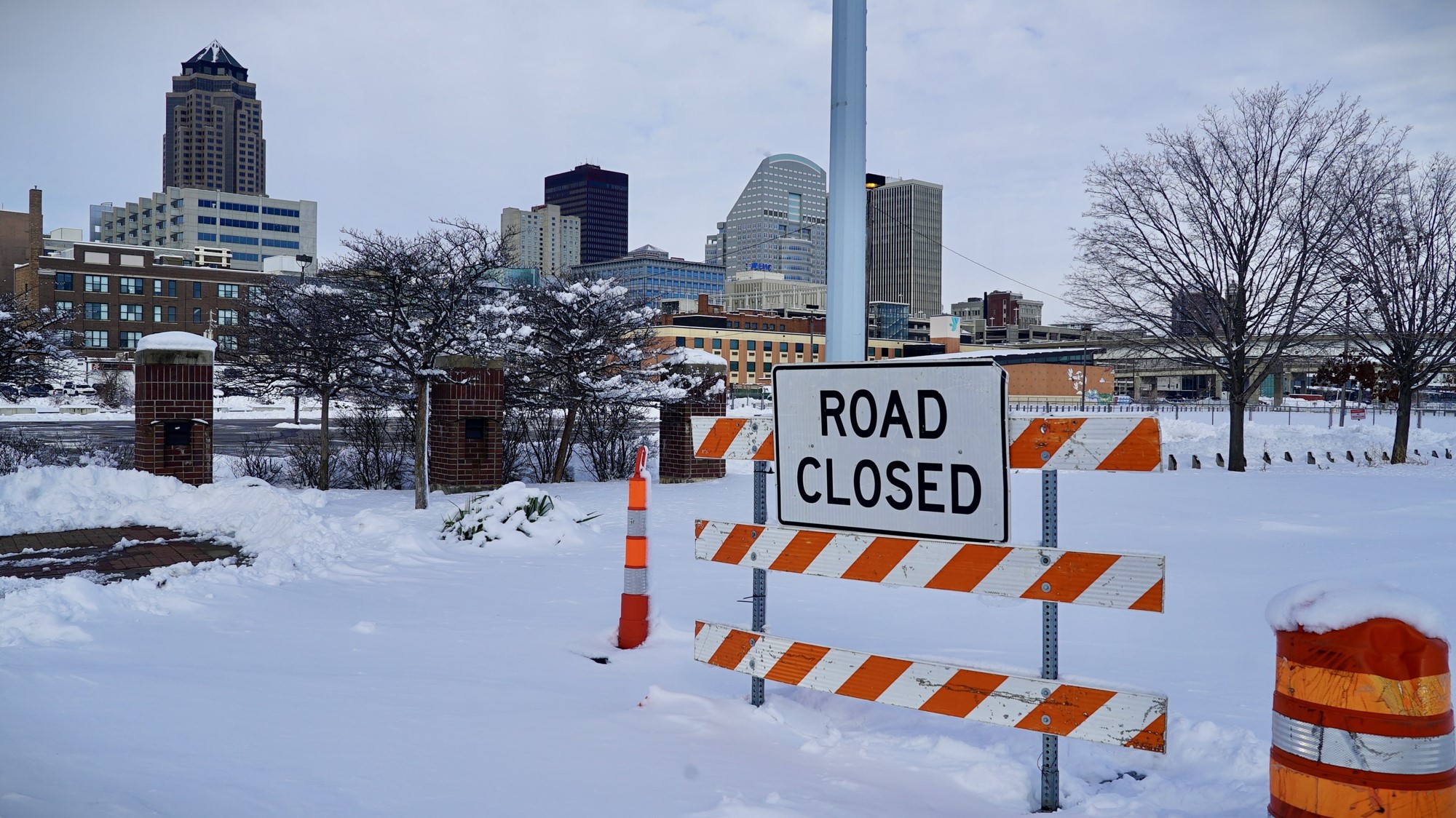 The Iowa skyline is in the background. A road closed sign stands on a snowy road in the foreground