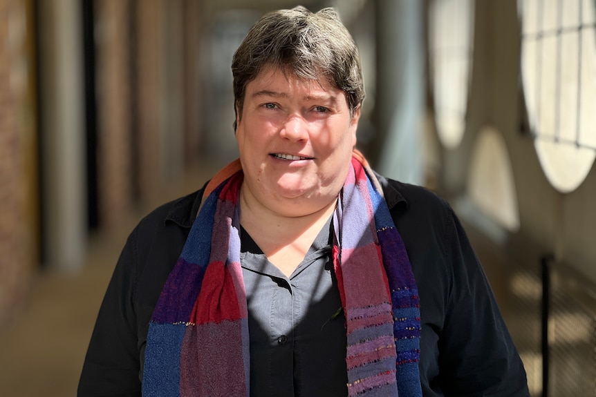 A woman wearing a black shirt and plaid scarf.