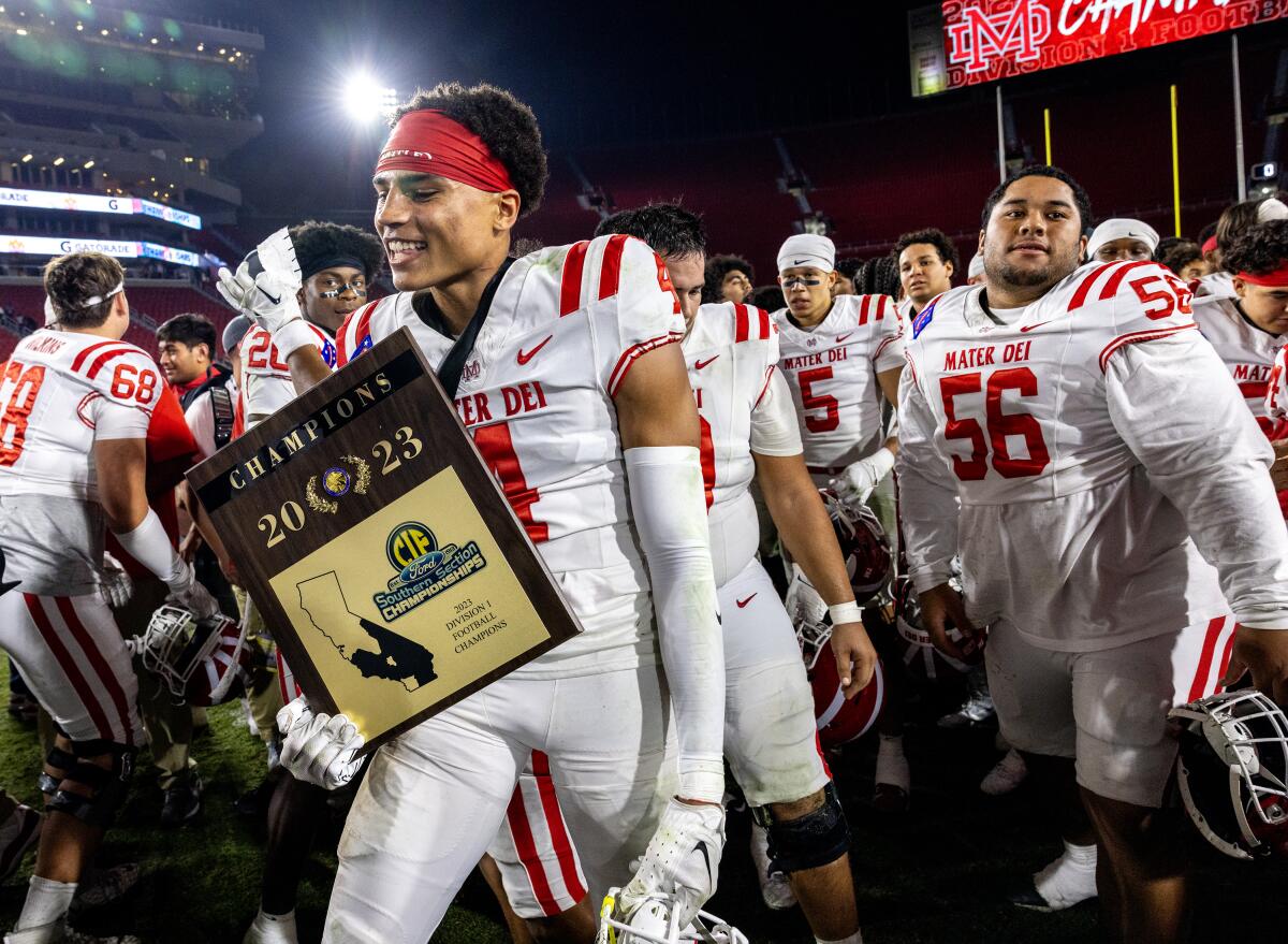 Zabien Brown holds championship trophy for Mater Dei.