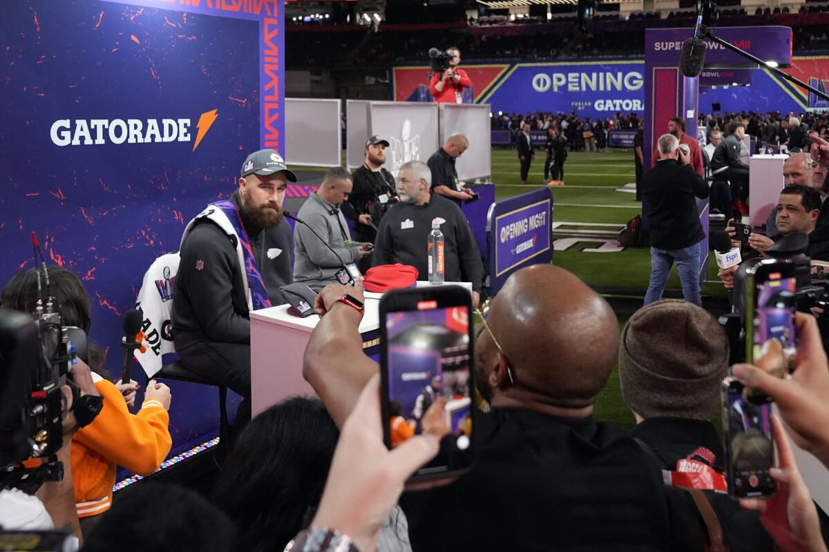 A man sits at a podium and people take photos of him