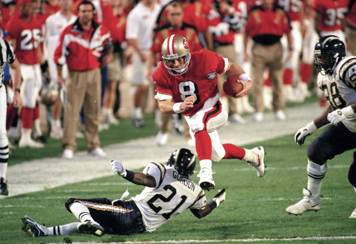 San Francisco quarterback Steve Young (8) runs over San Diego's Darrien Gordon (21) in Super Bowl XXIX.