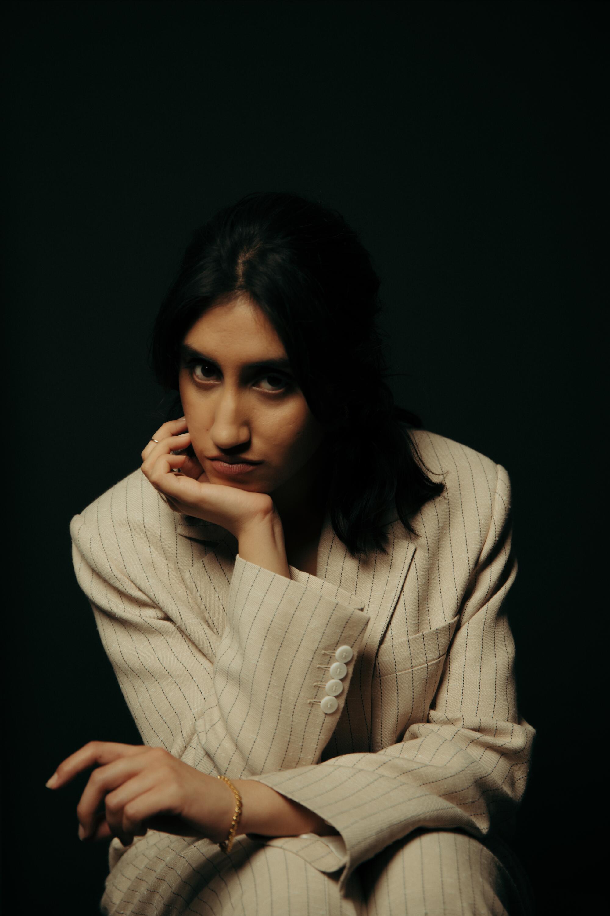 A woman sitting and resting her chin on her hand.