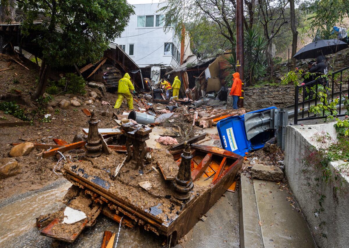 A piano lies in the middle of Caribou Lane as workers investigate a home pushed off its foundation by a mudslide