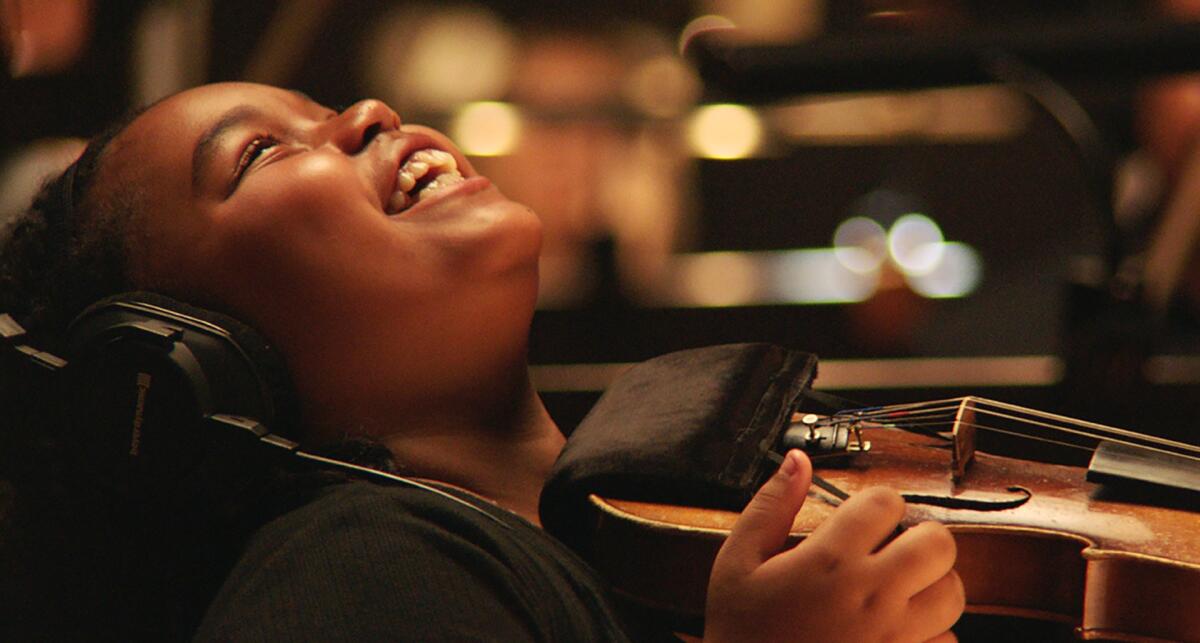 A child with a violin smiles.