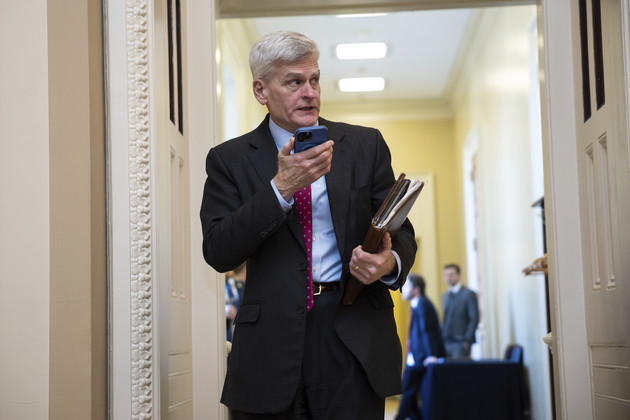 Bill Cassidy speaks into his phone while walking down the hall.