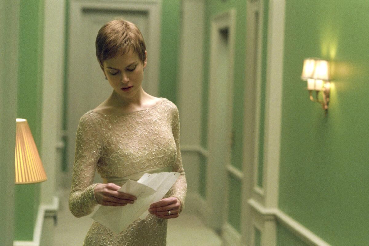 Actress Nicole Kidman looks at a piece of paper in a hallway with green walls and white trim