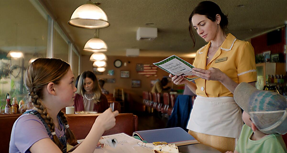 A young woman and a child sit at a diner table looking at their waitress in "Red, White and Blue."