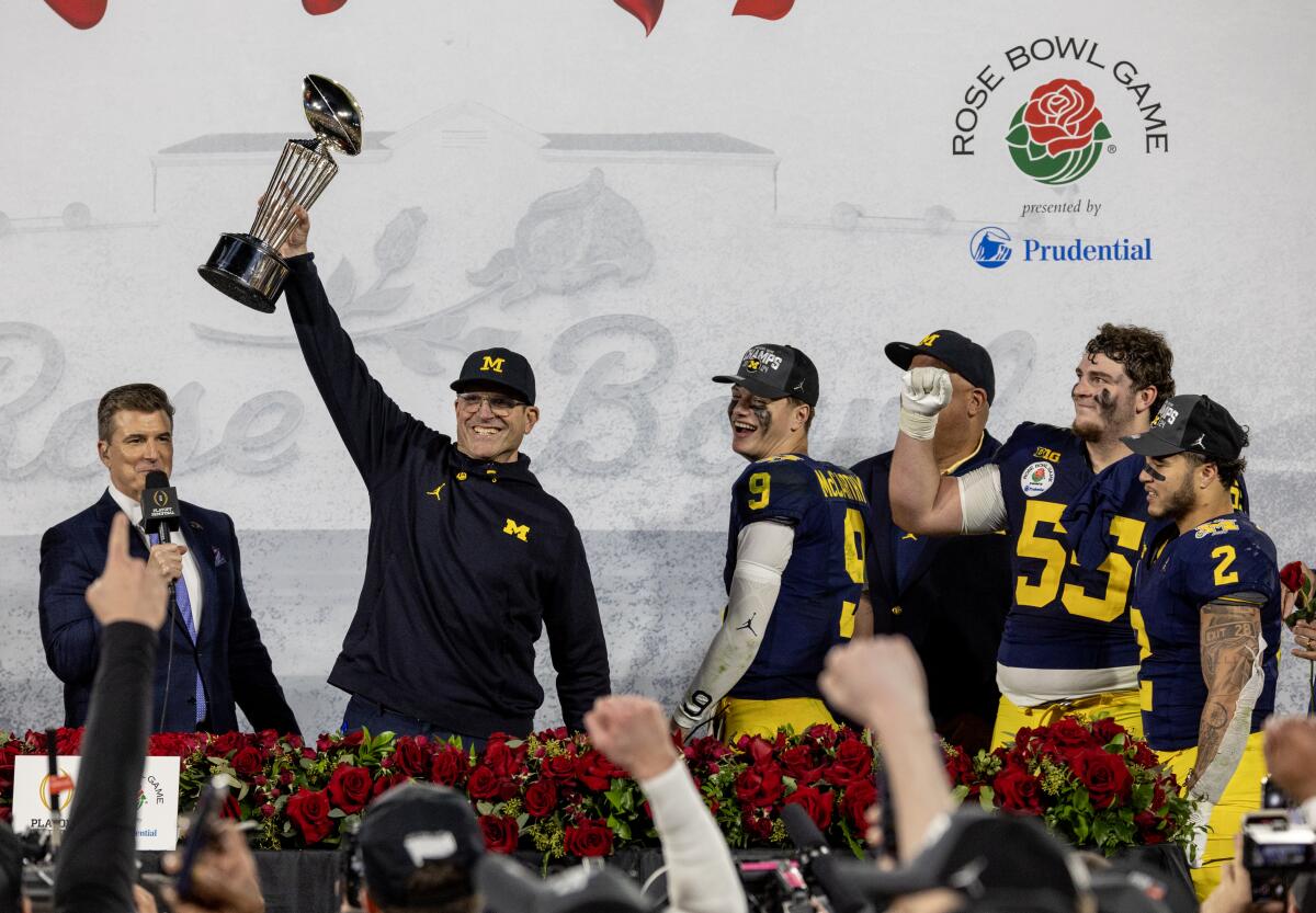 Michigan coach Jim Harbaugh holds the Rose Bowl trophy after the Wolverines’ win over Alabama.