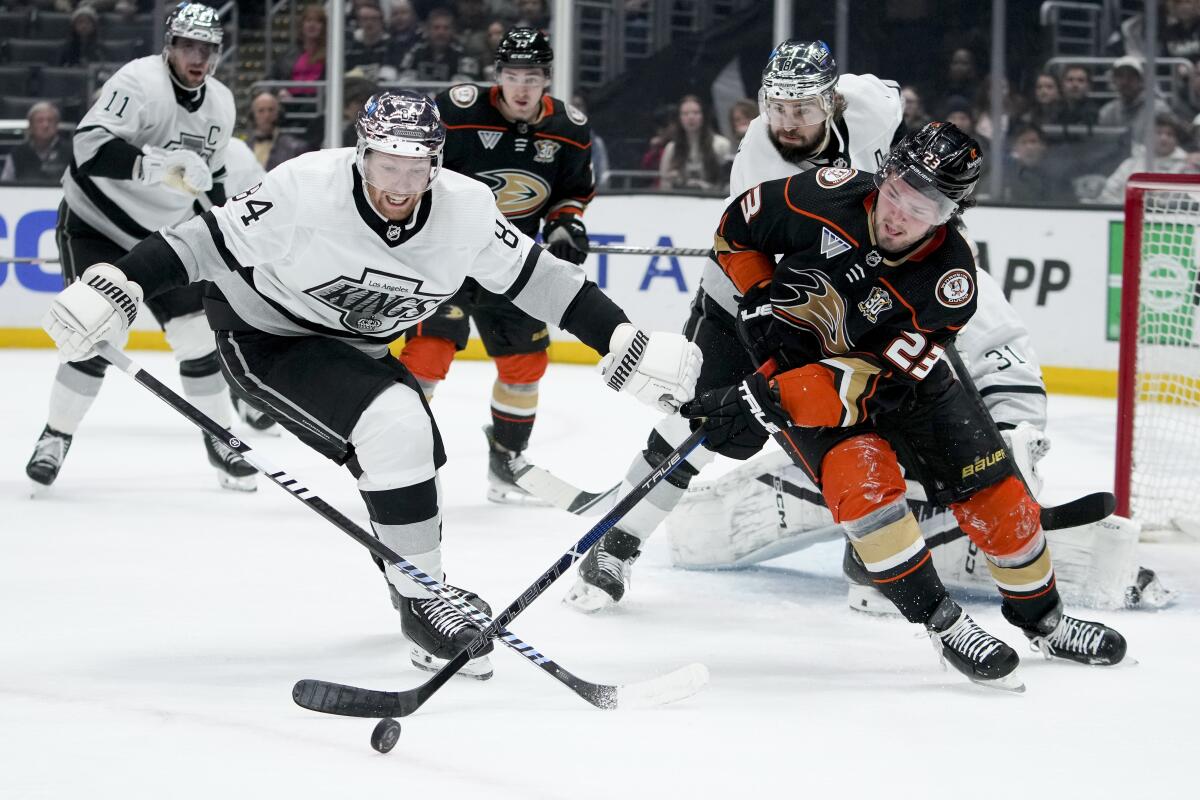 Kings defenseman Vladislav Gavrikov, left, battles Ducks and center Mason McTavish for the puck.