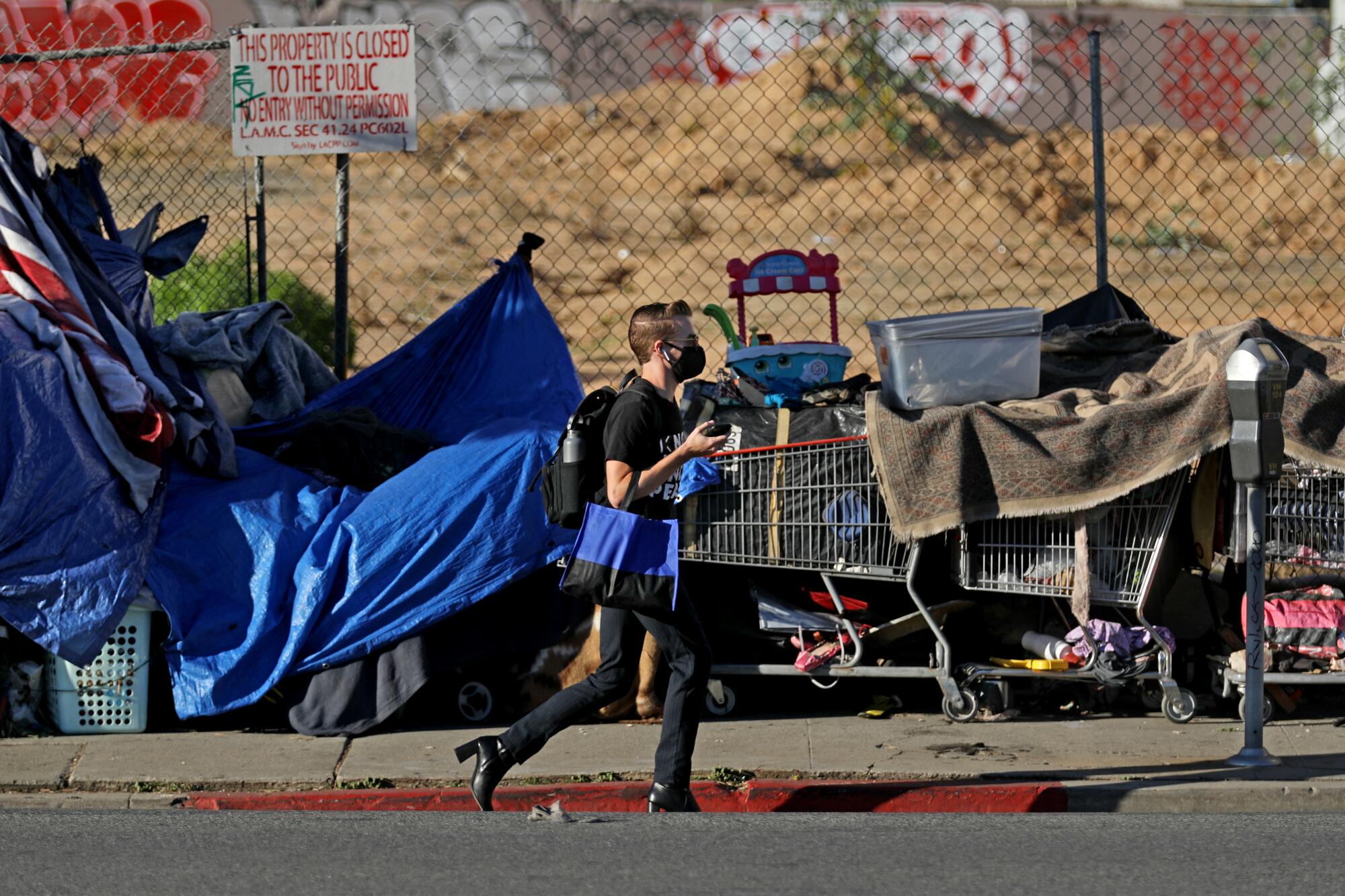 A pedestrian walks past a homeless encampment on Berendo Street in 2021.