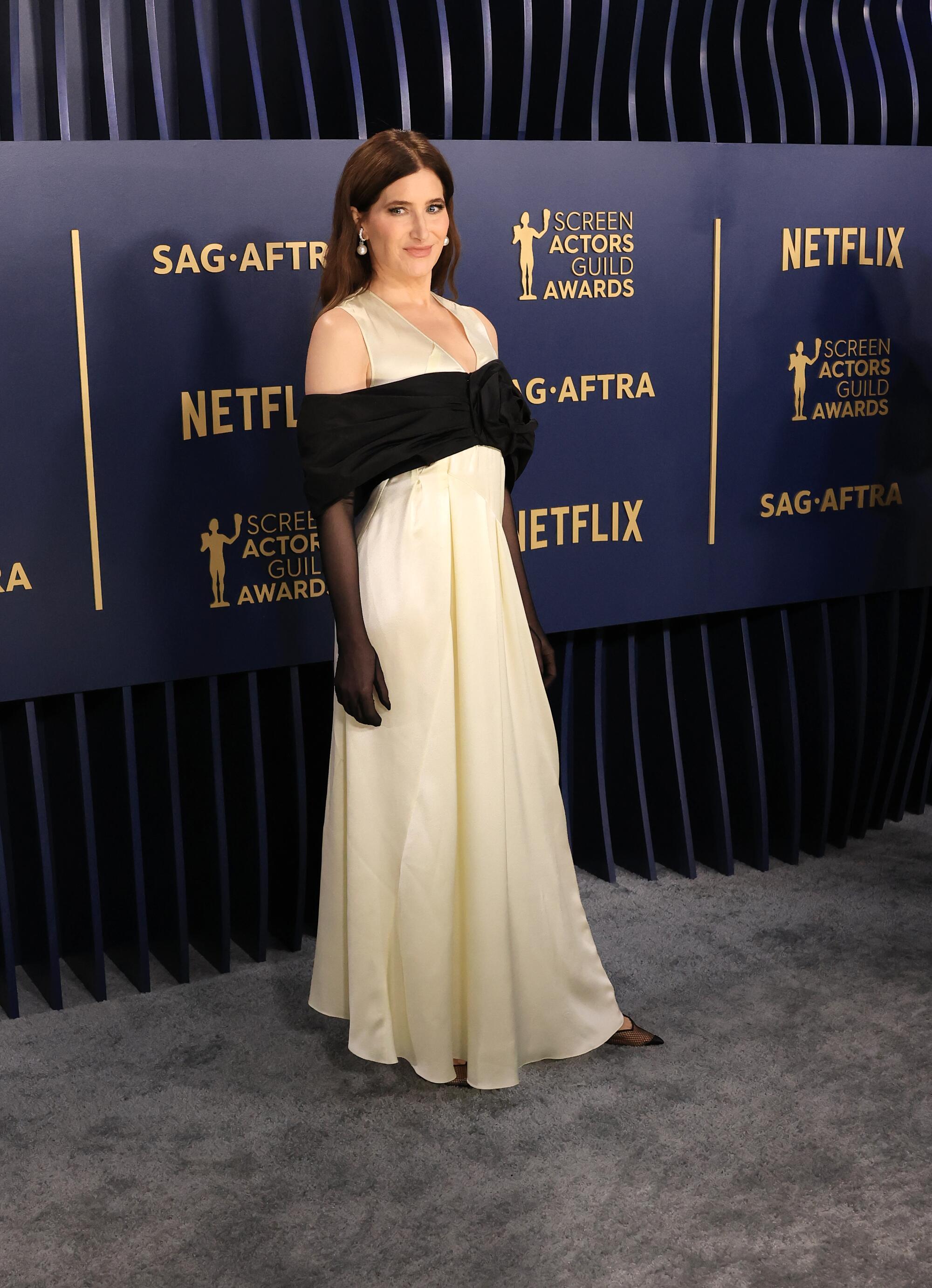 Kathryn Hahn wears a white dress with a black off-shoulder shawl at the SAG Awards. 