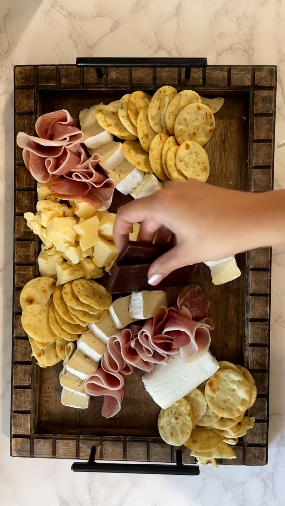 She assembled the cheeses, crackers, prosciutto, chocolate, and fruits she picked up