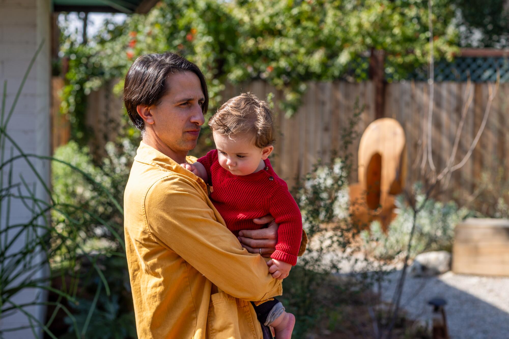 Vince Skelly holds his 10-month-old son in the backyard of the family home.