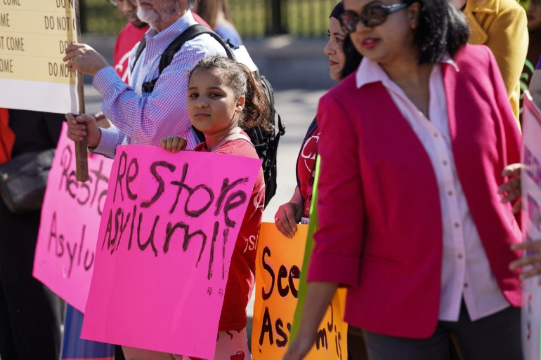 Demonstrators hold up handwritten signs in support of asylum rights.