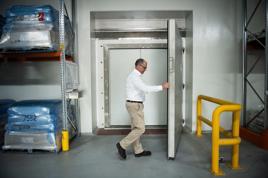 man mid way closing large steel door