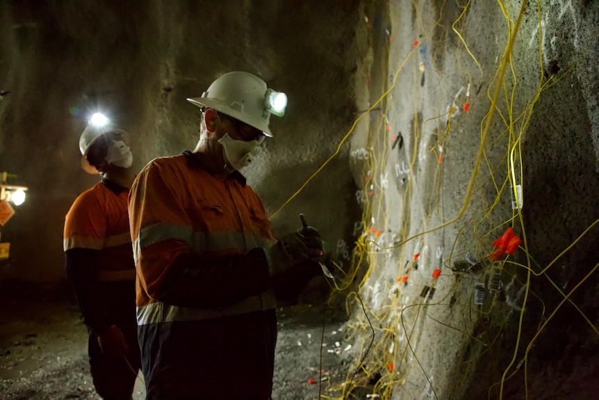 Two people in workplace safety gear lay detonation cord.