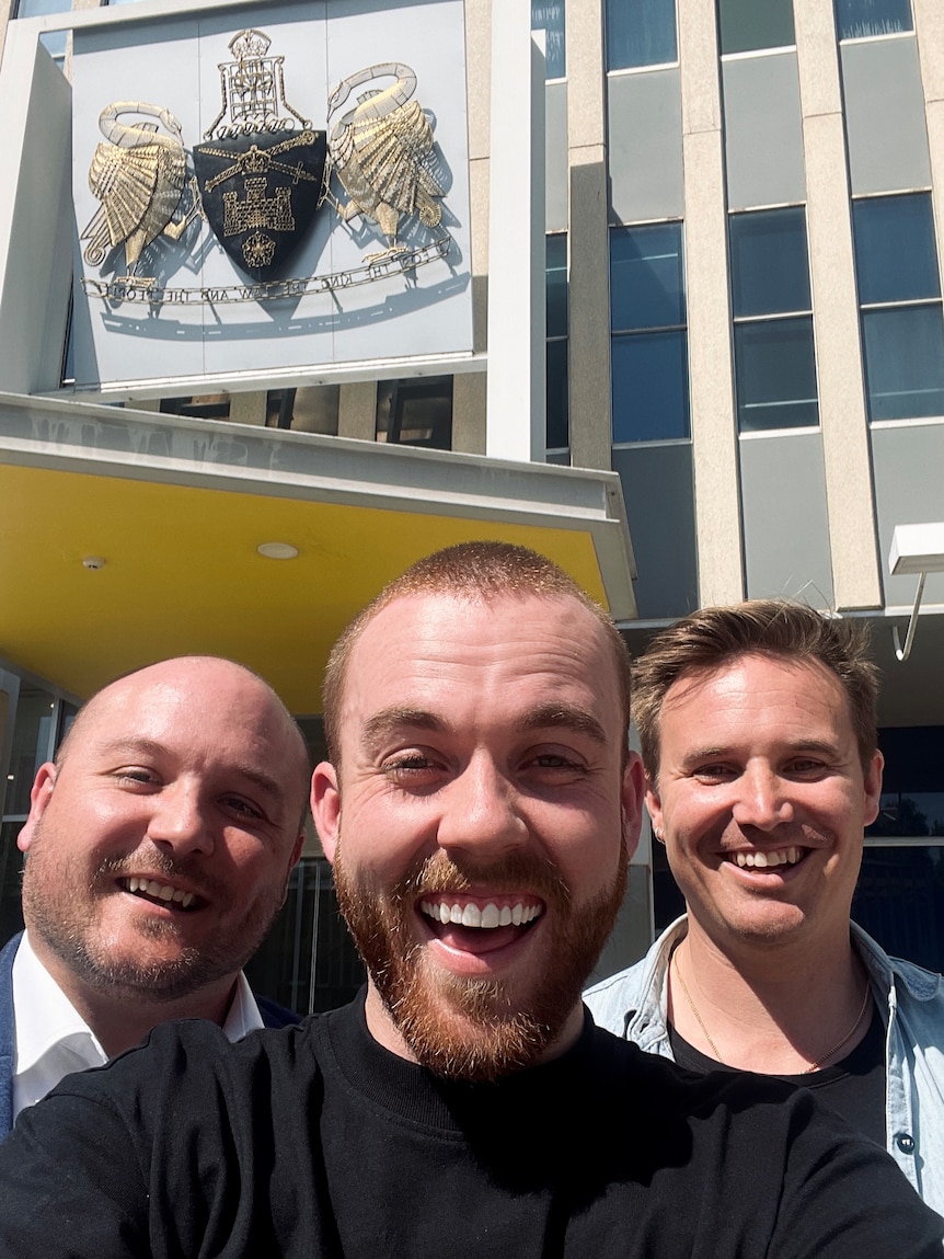 Three men outside the ACT Legislative Assembly smile.