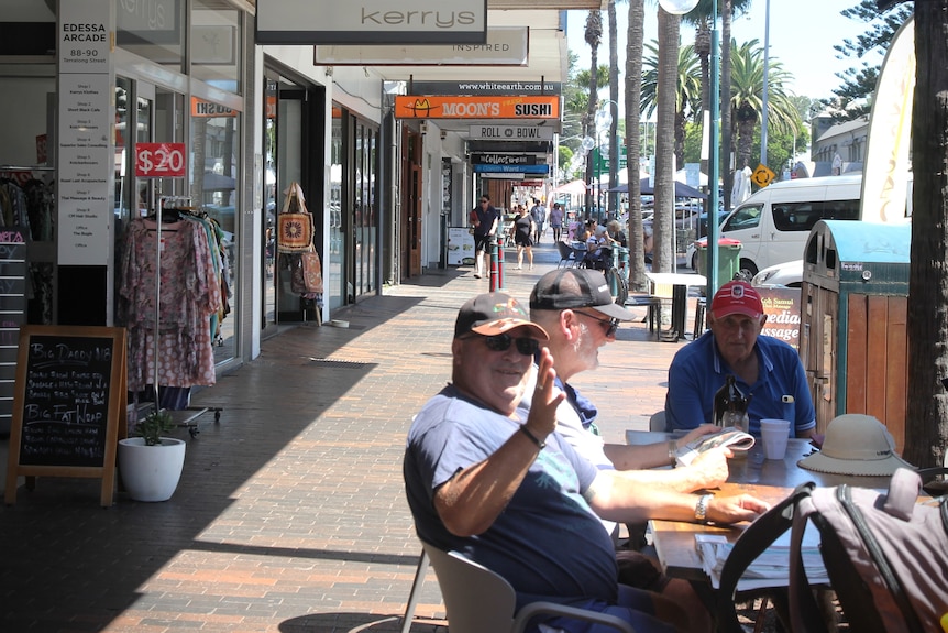 Man sitting at cafe waving, regional town main street