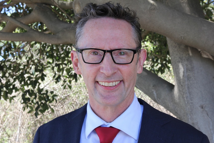 Dark hair man with glasses, wearing suit, smiling