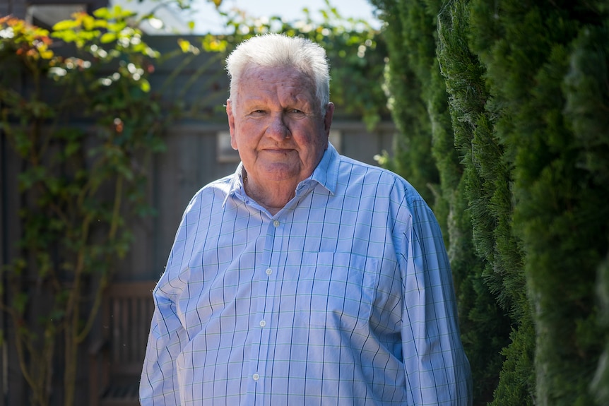 A man with white hair and a blue, long-sleeved shirt.