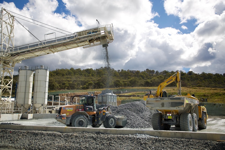 Machines deposit rock in a pile.