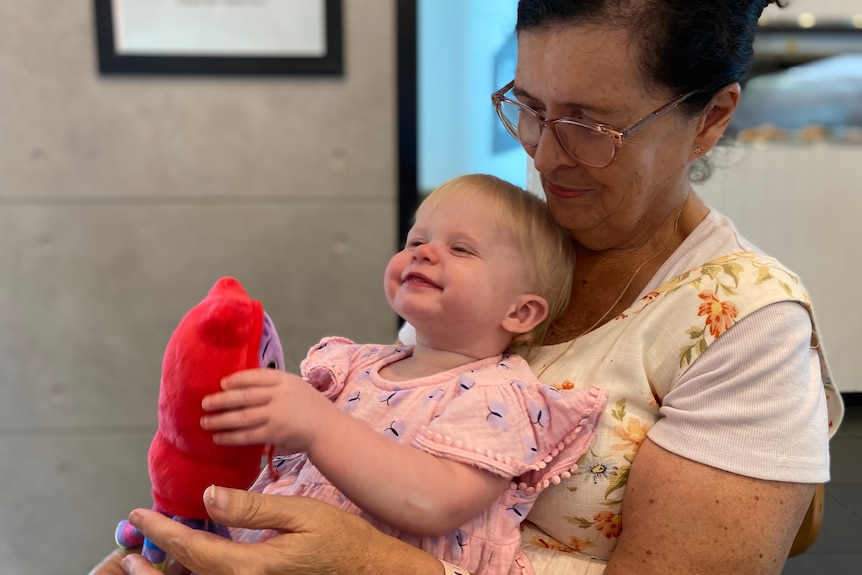 An older woman sits with a baby girl on her lap.