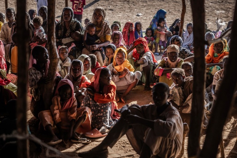 Sudanese refugees and ethnic South Sudanese families who have fled from the war in Sudan gather after crossing the border while waiting to be registered by the authorities at the Joda Border Crossing Point, near Renk