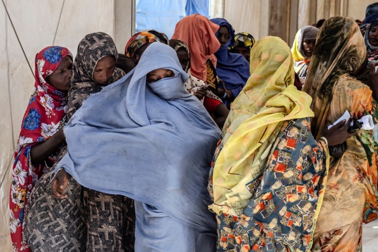 Sudanese refugees who have fled from the war in Sudan line up during a cash assistance programme at a Transit Centre for refugees in Renk