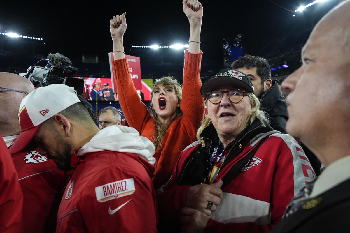 Taylor Swift, left, and Donna Kelce on field with postgame crowd