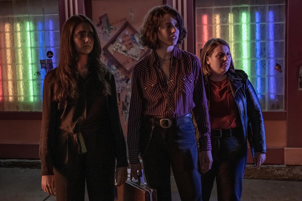 Three women stand outside a bar.