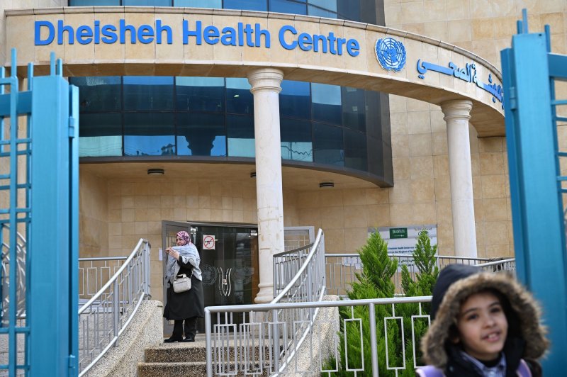 Palestinian refugees stand outside the entrance to the United Nations Relief and Works Agency for Palestinian Refugees Health Clinic in the Dheisheh refugee camp near Bethlehem, West Bank, on Tuesday. Photo by Debbie Hill/UPI