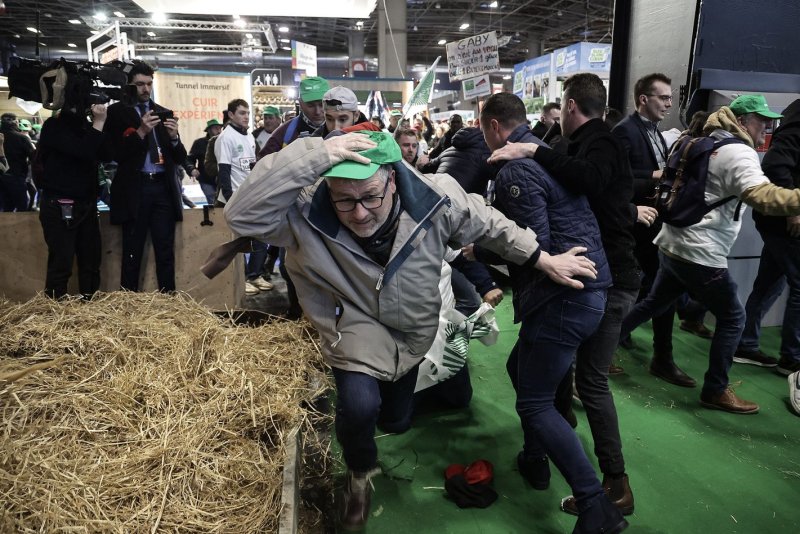 A farmer tries to run while protesting at the opening of the 60th International Agriculture Fair (Salon de l'Agriculture), in Paris on Saturday. The fair is being held amid months of demonstrations by farmers across Europe against the European Union's agricultural policies. Photo by Christophe Petit Tesson/EPA-EFE