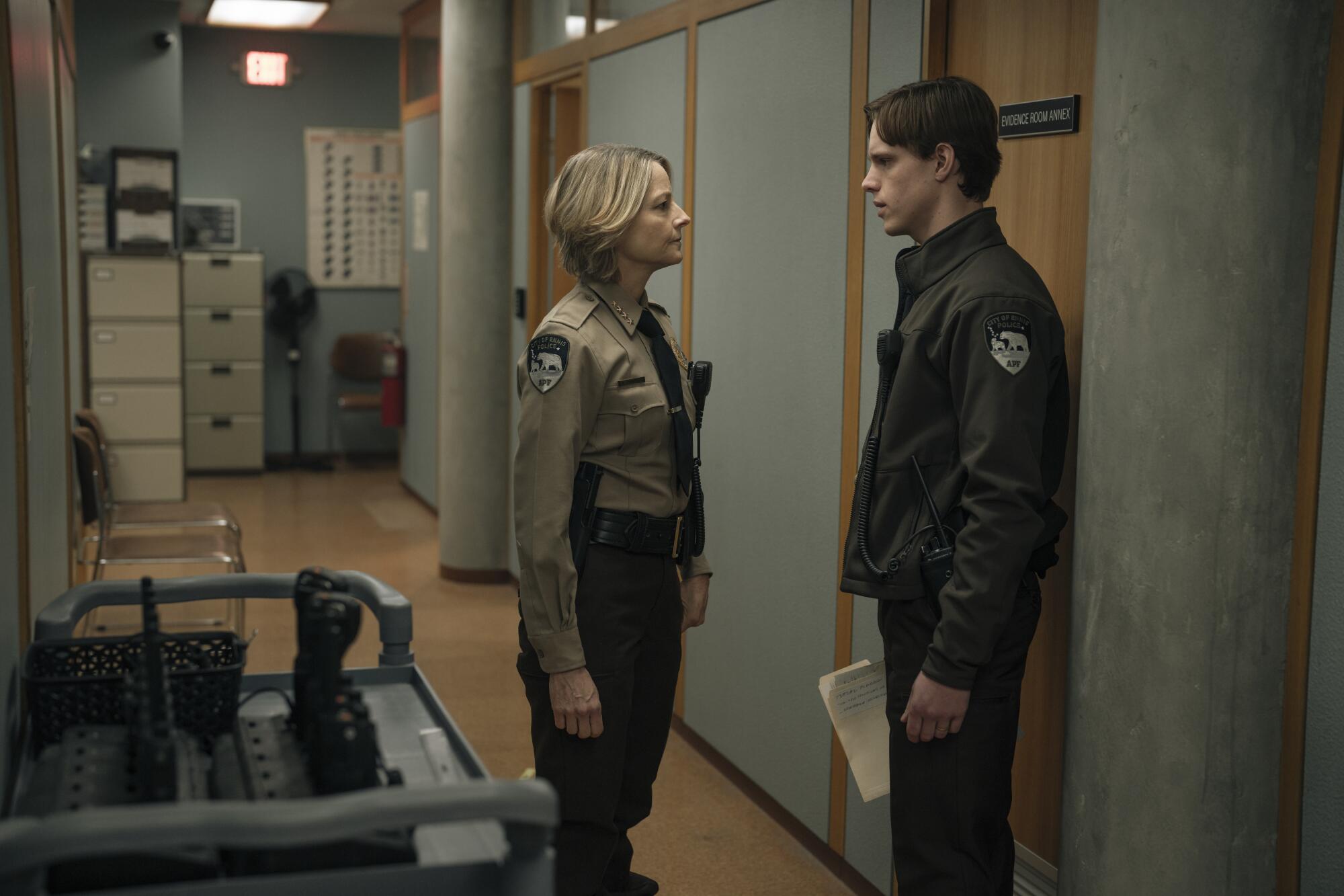 A female police officer stands in a hallway looking at a male officer.