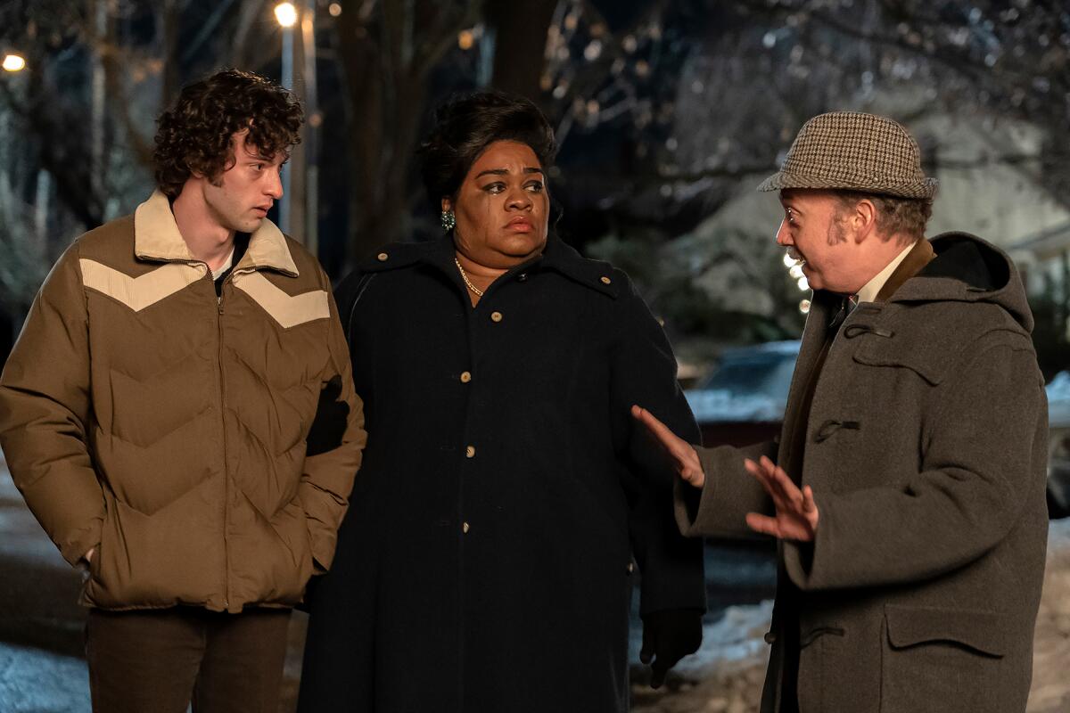 A teen and a man and woman walk outside in winter coats in "The Holdovers."