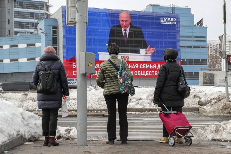 Three Moscovites watch Russian President Vladimir Putin deliver his annual address to the Federal Assembly beamed live onto a giant screen in the capital on Thursday. Photo by Maxim Shipenkov/EPA-EFE