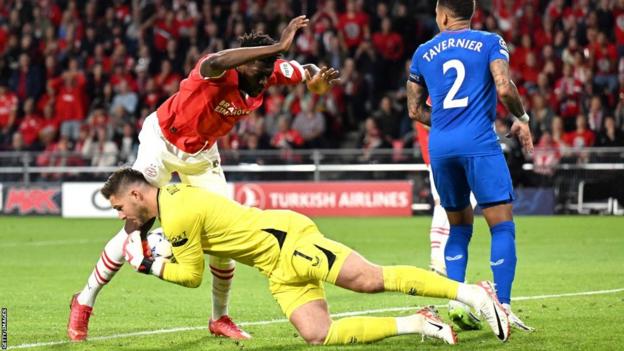 Jack Butland dives at a striker's feet while playing for Rangers