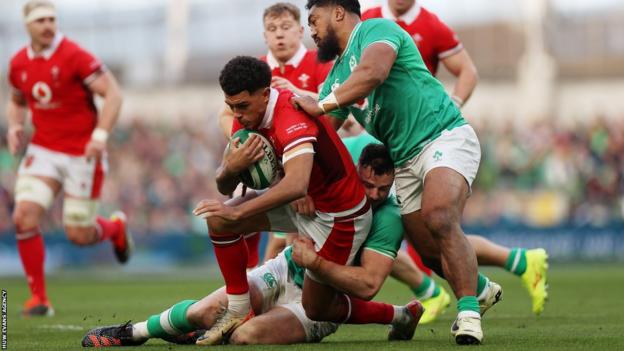 Rio Dyer is tackled by Irish players